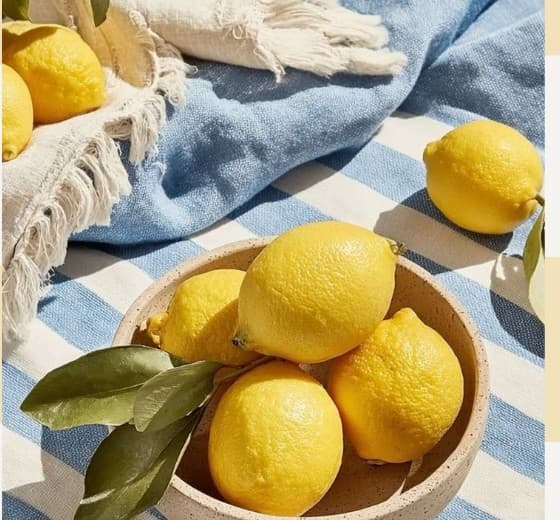 Bowl of fresh lemons styled on a blue gingham cloth